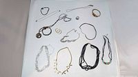 Overview of 14 assorted jewelry pieces laid on white background