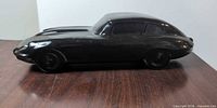 right side profile of black ceramic Jaguar E-Type style sculpture on wood surface