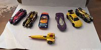 Seven Hot Wheels cars laid out on white background