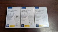 Front view of three sealed Insignia dual-port car charger boxes