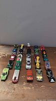Three rows of die-cast cars on wooden surface showing full lot