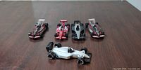 Five die-cast Formula 1 cars lined up on wood surface