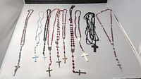 Overview of nine rosaries laid out showing bead colors, crucifixes and medals