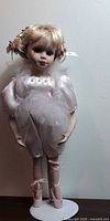 Full view of porcelain ballerina doll on stand