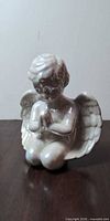 Front view of glossy porcelain cherub figurine