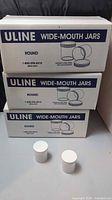 Three sealed Uline jar cases with two loose jars in front