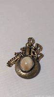 Front view showing agate cabochon set in brass pendant with chain
