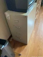 Front view of beige two-drawer metal file cabinet with lock