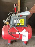 Red Central Pneumatic 3 gal air compressor showing tank, motor housing, pressure regulator, and attached tag number