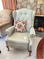 Front view of light green wingback armchair with pillow