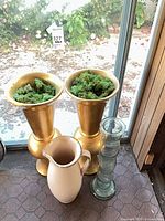 Group shot showing all four items: two gold urn vases with moss filler, cream pitcher, clear glass vase