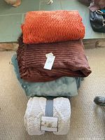 Stack of four throw blankets showing colors and textures