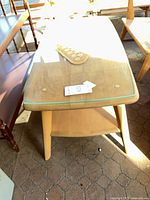 Overall view of light wood coffee table with glass top and lower shelf