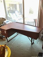 Full view of teak veneer desk showing shape, legs and finish