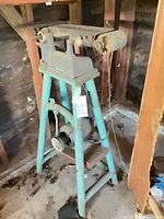 Full view of bench sander-grinder showing sanding arm, motor, frame and pulley system