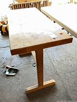 Angled view of solid wood trestle table showing top surface wear and T-shaped foot