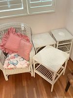white wicker armchair with three cushions beside three white wicker nesting tables
