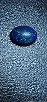Front view of oval black opal showing pinfire pattern