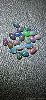 Group of oval black opal cabochons showing play-of-color