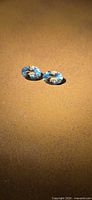 Pair of light blue oval gemstones on surface