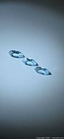Three marquise-cut sky blue topaz gemstones on neutral background