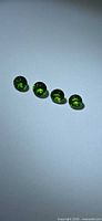 Four round green gemstones on neutral background