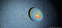Front view of oval cabochon opal showing multicolored flashes