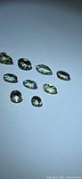 Group of nine lemon-lime tanzanite gemstones arranged on neutral background
