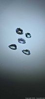 Five faceted aqua to violet-blue tanzanite gemstones on neutral background