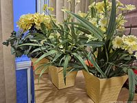 Three artificial flower arrangements in yellow pots on table