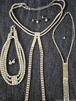 Overview of three necklaces and assorted earrings on dark fabric background