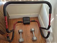 Ab roller frame and two hex dumbbells on floor