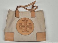 Front view showing Tory Burch logo, canvas body, leather trim