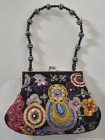 Front view of purse showing overall shape, beaded handle, clasp and embroidered sequin design