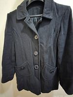 Front view of black coat showing buttons, collar, pockets
