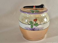Overall view of small ceramic jar with lid showing floral design and pipe finial