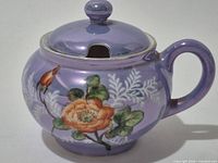 Front view of lavender Noritake porcelain sugar jar with floral design and handle