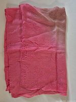 Full view of folded pink silk scarf showing size and overall color