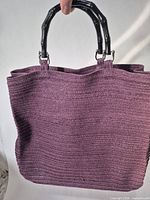 Front view of purple woven tote with black ring handles