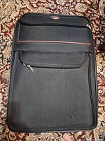 Front view of black suitcase showing exterior pocket and overall condition