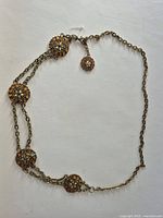 Full view of belt showing five medallions, chain arrangement, and beaded terminal drop