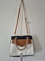 Front view of color-block handbag hanging with strap