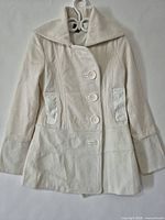 Full front view of ivory textured jacket on hanger showing collar, buttons, pocket placement, overall length