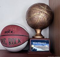 Autographed Spalding basketball beside bronze-tone basketball trophy on wood base