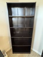 Front view of full-height black bookcase with five shelves