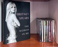 Book ‘The Woman in Me’ displayed beside stack of nine Britney Spears CDs for scale