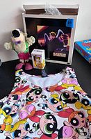 Tank top, plush toy, boxed mini figure, Harvey Birdman poster grouped on surface