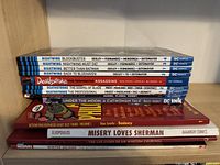 Spine view of stacked graphic novels highlighting titles and publishers