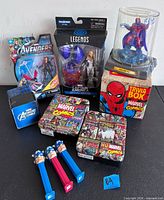 Group shot showing all items: boxed Captain America Legends figure, blister-pack Avengers figure, Magneto dome, three PEZ dispensers, Marvel trivia box, Avengers tin, and two Marvel collage tins