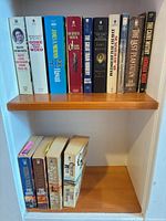 Front view of two shelves showing all 16 mass-market paperbacks